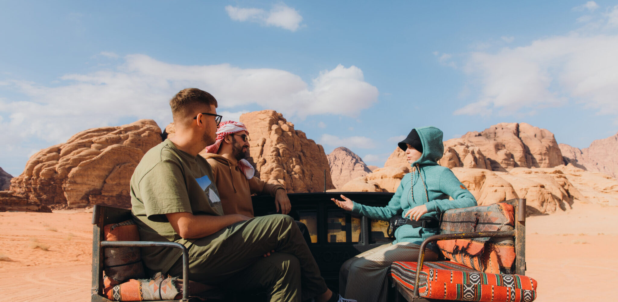 Happy two males and one female travelers enjoying a road trip by 4x4 vehicle  car at the red mountain desert in Jordan
